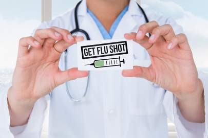 Doctor holding a sign that says, 'get flu shot'